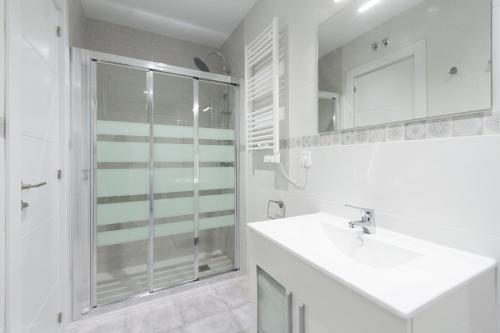 a white bathroom with a shower and a sink at Urbantec Realty - Plaza de Castilla in Madrid
