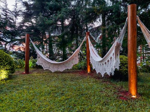 two hammocks hanging from poles in a yard at Pousada Victoria Villa By Nacional Inn - A 800 metros da Vila Capivari in Campos do Jordão
