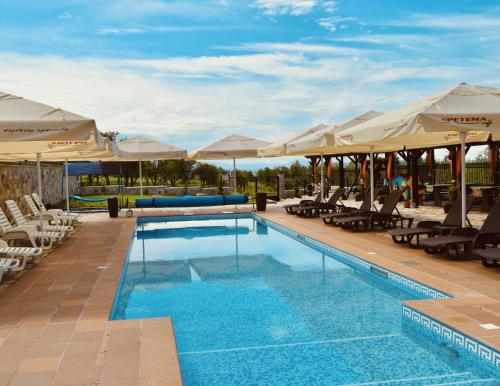 a swimming pool with lounge chairs and umbrellas at Asya Guest House in Sapareva Banya