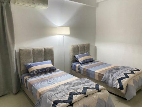 um quarto com duas camas e um candeeiro em 休闲民宿 Leisure Homestay @The Venus Sitiawan em Kampong Lumut Kiri
