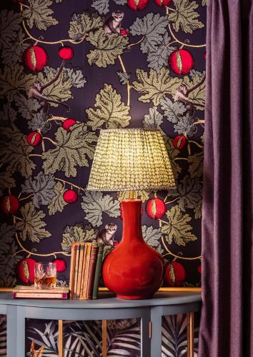 a red vase sitting on a table with a lamp at The Portobello Hotel in London