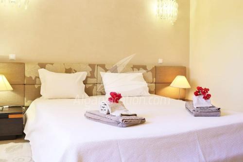 a bedroom with a large white bed with red flowers on it at Villa Felicity in Porches