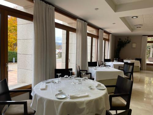 a restaurant with white tables and chairs and large windows at Parador de Puebla de Sanabria in Puebla de Sanabria