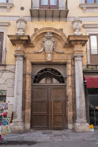 a large wooden door on a building with columns at 124 Maqueda Apartments in Palermo