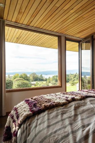 a bedroom with a bed and a large window at Lujosa Casa Altamira vista al lago e Isla Aillaquillen in Villarrica