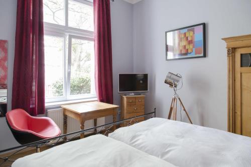 a bedroom with a bed and a chair and a window at Hotel Residenz Begaswinkel in Berlin