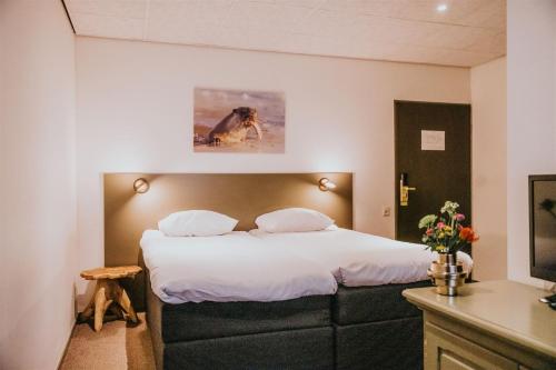 een slaapkamer met een groot bed met witte lakens bij Hotel Sportsbar & Brasserie Dorhout Mees in Biddinghuizen