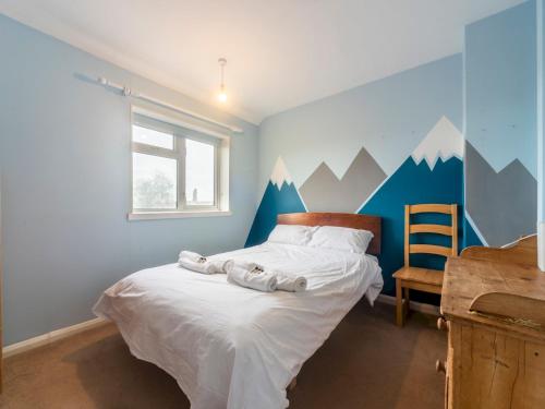 a bedroom with a bed with white sheets and mountains painted on the wall at Pass the Keys Comfortable 2bedroom home with free parking in Twickenham