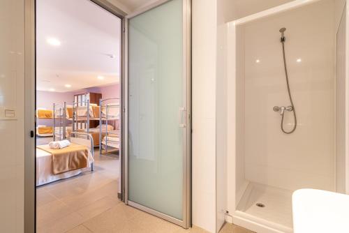 - Baño con puerta de ducha de cristal y dormitorio en Albergue "El Río", en Cella