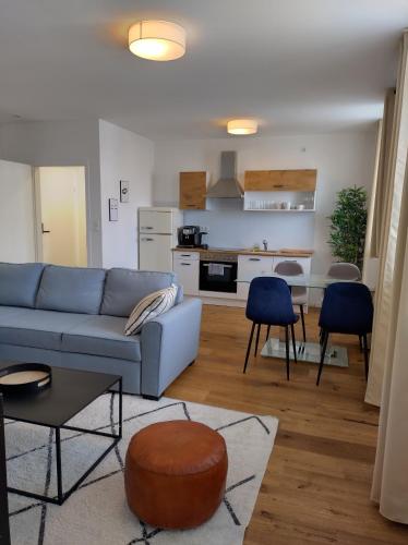 DOWA Apartments Thaliastrasse في فيينا: غرفة معيشة مع أريكة زرقاء ومطبخ