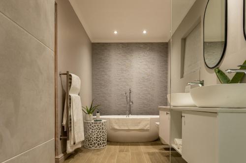 ein Badezimmer mit einer weißen Badewanne und einem Waschbecken in der Unterkunft Villa Stellenbosch in Stellenbosch