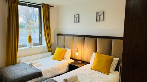 a bedroom with two beds with yellow pillows and a window at Naps Inn in Birmingham