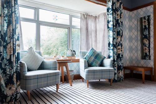 a living room with two chairs and a table and a window at The Inn on the Moor Hotel in Goathland