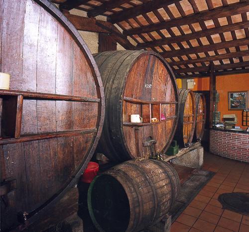 um grupo de barris de vinho de madeira numa sala em Hostal Mallorquines em Riudarenes