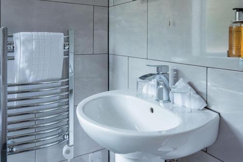a white bathroom with a sink and a towel rack at The Inn on the Moor Hotel in Goathland