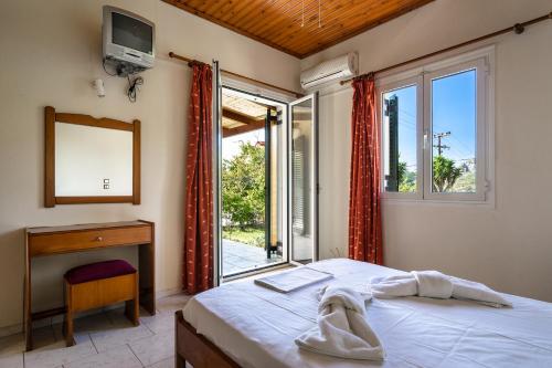 a bedroom with a bed and a desk and a window at Pantelios Village apartment 1 in Kefallonia