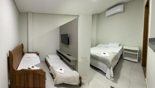 um pequeno quarto com duas camas e uma televisão em Confort Flats em Bonito