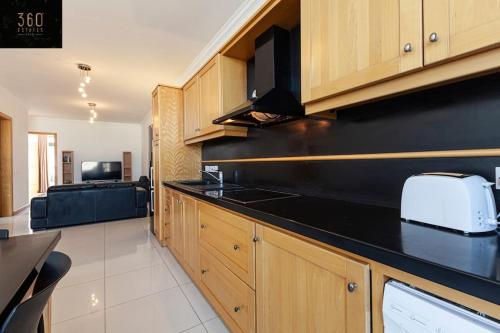 eine Küche mit einer schwarzen Arbeitsplatte und ein Wohnzimmer in der Unterkunft Comfortable Penthouse, served with LIFT, WIFI & AC by 360 Estates in Gżira