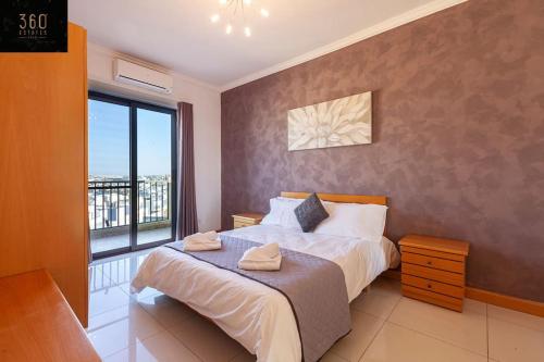 ein Schlafzimmer mit einem großen Bett und einem großen Fenster in der Unterkunft Comfortable Penthouse, served with LIFT, WIFI & AC by 360 Estates in Gżira