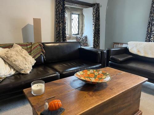 a living room with a leather couch and a wooden coffee table at Beautiful listed 3 bedroom cottage with wood burner in Youlgreave