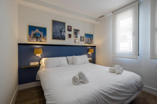 a bedroom with a large white bed with two stuffed animals on it at Wello Apartments Sevilla in Seville