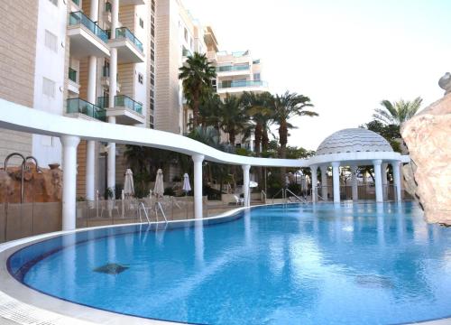 a large swimming pool with a gazebo next to a building at Stylish 3BR Golf Residence Eilat in Eilat