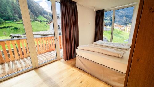 Cette chambre dispose d'un balcon avec une grande fenêtre. dans l'établissement All-Suite Resort Zwieselstein - Sölden, à Sölden