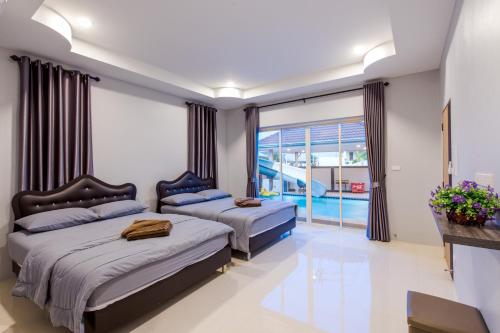 a bedroom with two beds and a large window at Norway Poolvilla in Cha Am