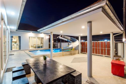 een huis met een zwembad en een tafel en een glijbaan bij Norway Poolvilla in Cha Am