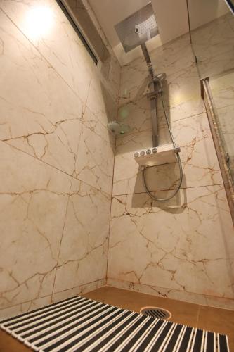a corner of a shower in a room with a marble wall at Hotel Holy Vivasa in Rishīkesh