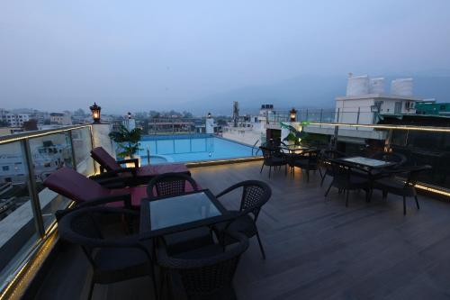 a balcony with tables and chairs and a pool at Hotel Holy Vivasa in Rishīkesh