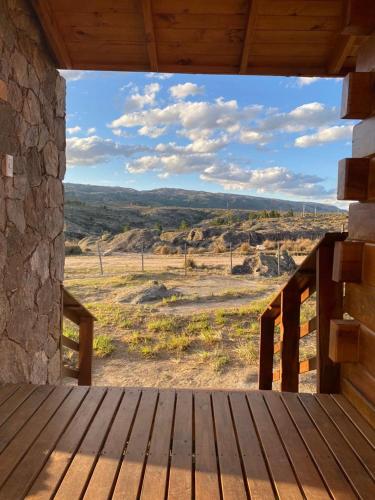 a wooden porch with a view of a field at Alma Serrana - Suites de montaña! in La Cumbrecita