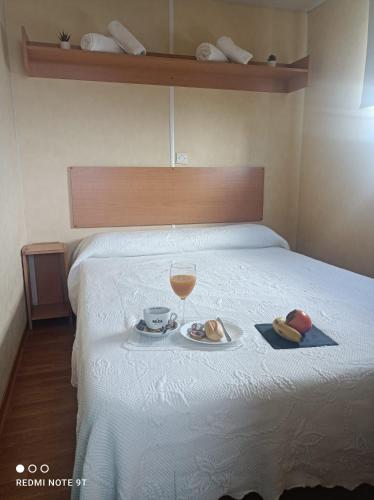 a bed with a glass of wine and a plate of food at Bungalows Buda Beach in Sanlúcar de Barrameda