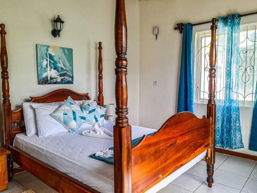 a bedroom with a large wooden bed with blue curtains at Sunrise Bliss Villa with Hot Tub, King Bed, Ocean, and Mountain View in La Plaine