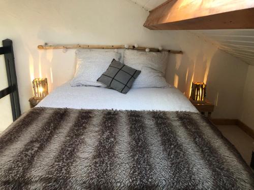 a bed with a black and white comforter in a room at LE NID DOUILLET in Ore