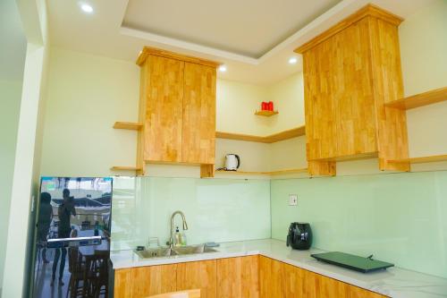 a kitchen with wooden cabinets and a sink at TUY HOA CASA in Liên Trì (3)