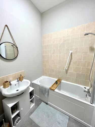 een badkamer met een wastafel, een bad en een spiegel bij Stevenson Apartment in Alexandria