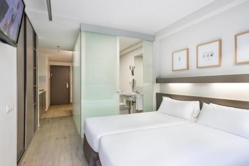 a bedroom with a large white bed and a bathroom at Aparthotel Bcn Montjuic in Barcelona