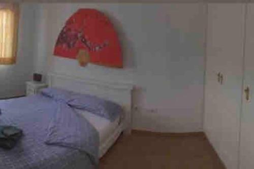 a bedroom with a bed and a red painting on the wall at Alojamientos Vistas Edén 67 in Caleta De Fuste