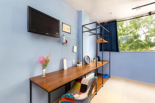 een thuiskantoor met een bureau en een tv aan de muur bij Hoàng Phi Hotel in Ho Chi Minh-stad