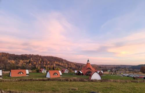 a group of tents and a church in a field at Hunnia - Huntanya in Vlăhiţa