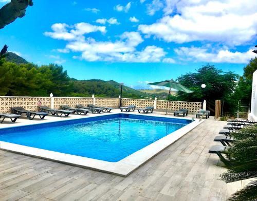 a swimming pool with chairs and an umbrella at Villa Alexa this charming villa is just a 10 min drive to either Playa Den Bossa or San Antonio in Sant Josep de sa Talaia