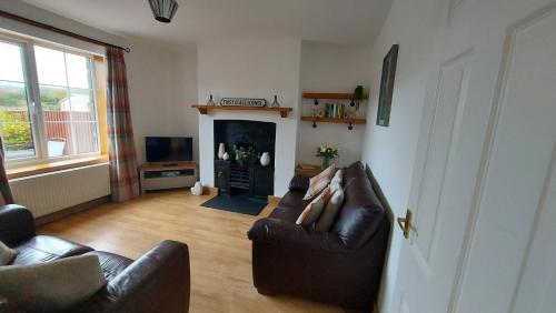 a living room with a couch and a fireplace at Railway Cottage in Conwy