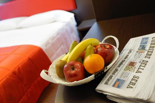 a bowl of fruit on a table next to a newspaper at Hotel al Corso in Legnano