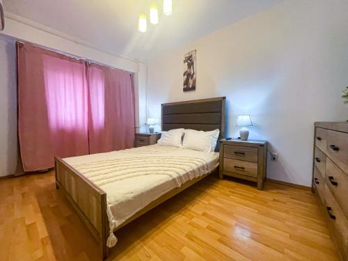 1 dormitorio con 1 cama grande y suelo de madera en National Arena Mega Mall Elana apartment, en Bucarest