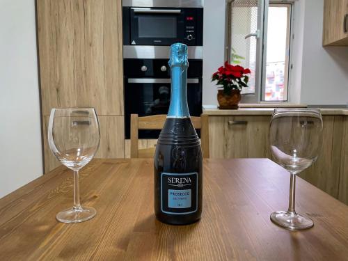 a bottle of wine sitting on a table with two wine glasses at National Arena Mega Mall Elana apartment in Bucharest