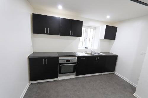 - une cuisine avec des placards noirs et un évier dans l'établissement Homeday cultivateur n°2 appartement type F3, à Haguenau