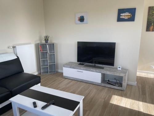ein Wohnzimmer mit einem schwarzen Sofa und einem Flachbild-TV in der Unterkunft Ty Enez Mor in Lanildut