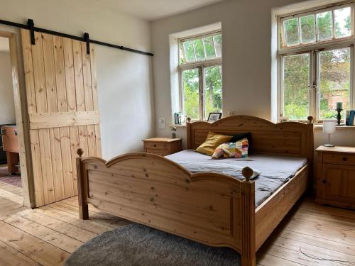 a bedroom with a large wooden bed and windows at Wendlandhof Lüggau in Dannenberg