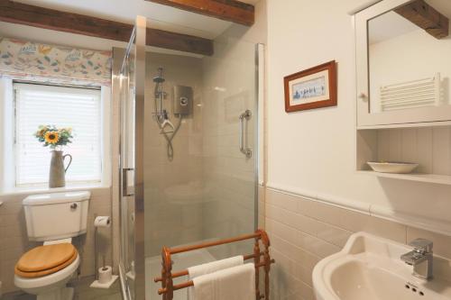 a bathroom with a shower and a toilet and a sink at Weavers Cottage by Weavers of Haworth in Haworth